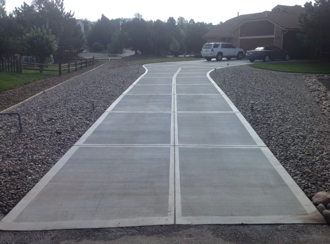 Curved concrete driveway with gravel landscaping in a suburban setting.
