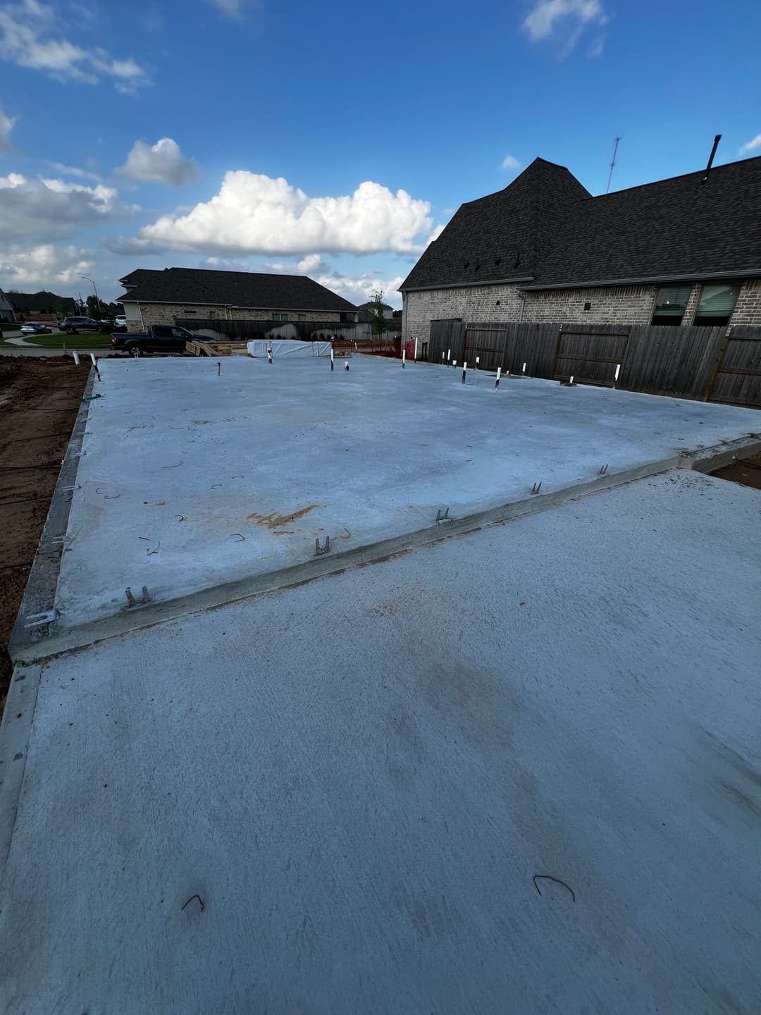 Concrete foundation slab for new home construction under a clear blue sky.